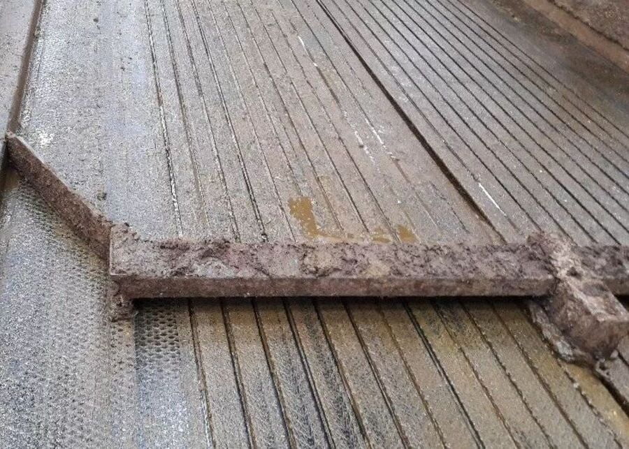 An automatic manure scraper cleaning a walkway covered with rubber mats