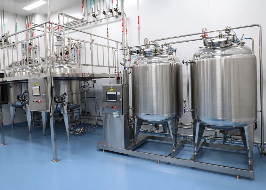 Industrial stainless steel CIP cleaning system integrated with automated dairy processing tanks in a hygienic workshop.