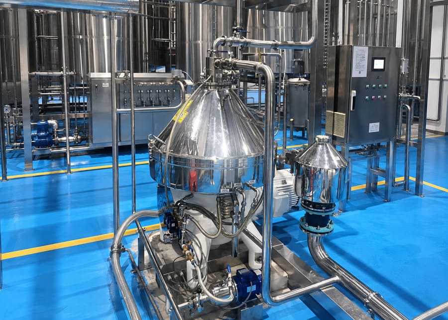 Industrial stainless steel disc stack centrifugal clarifier separator with PLC control panel integrated into an automated dairy processing production line