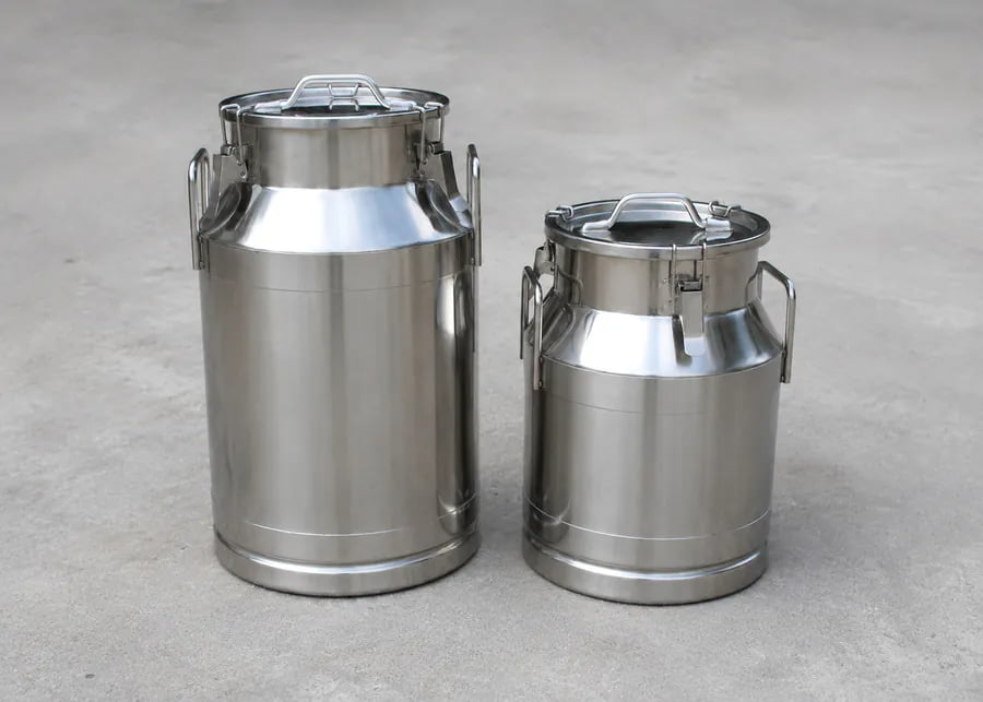 Two industrial-grade stainless steel milk cans used for safe raw milk transport to prevent early contamination.