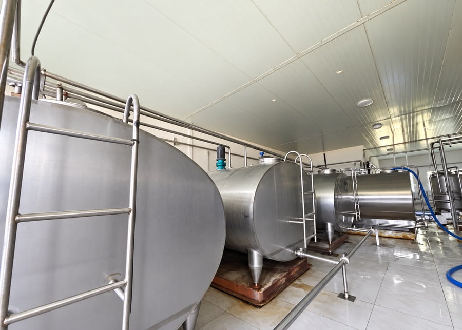 Multiple stainless steel bulk milk cooling tanks under evaluation at a customer dairy farm facility.